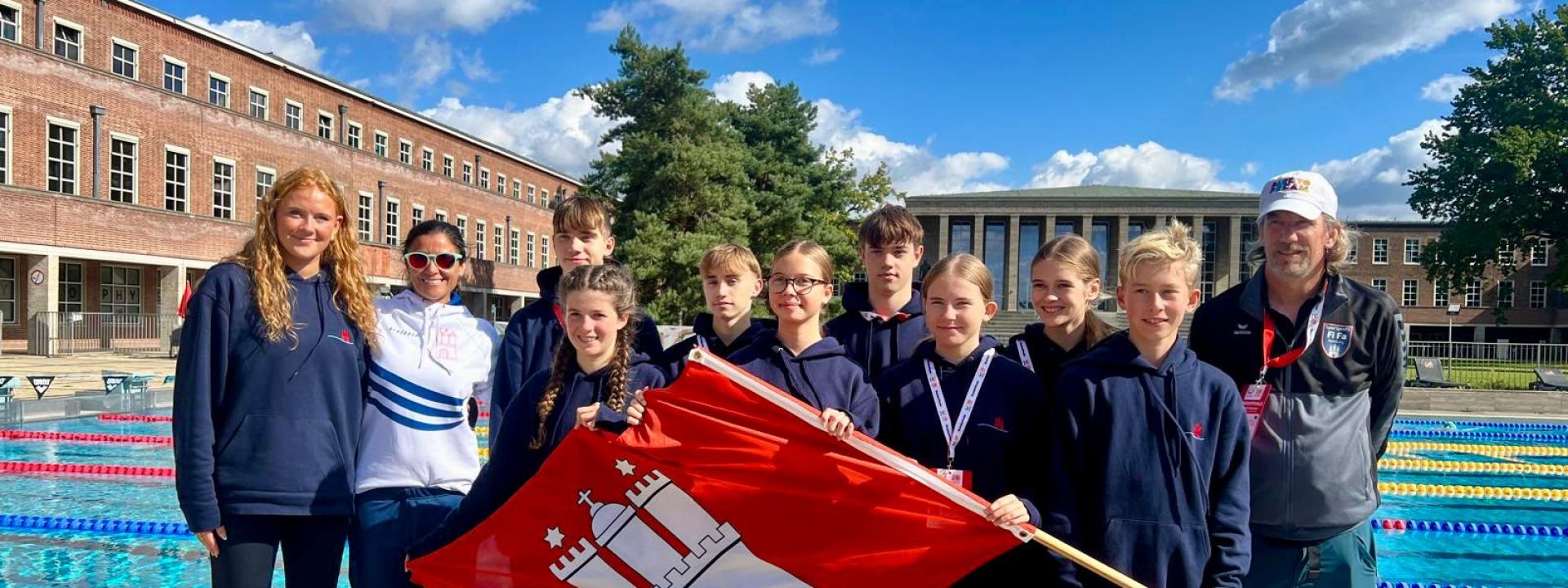 Das Team der StS Fischbek-Falkenberg mit Betreuerinnen und Betreuern und der Hamburg-Flagge am Olympiabad in Berlin.