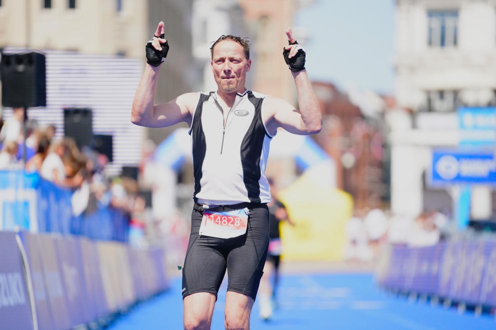 Ein Jedermann-Finisher überquert jubelnd die Ziellinie beim Suzuki World Triathlon Hamburg.