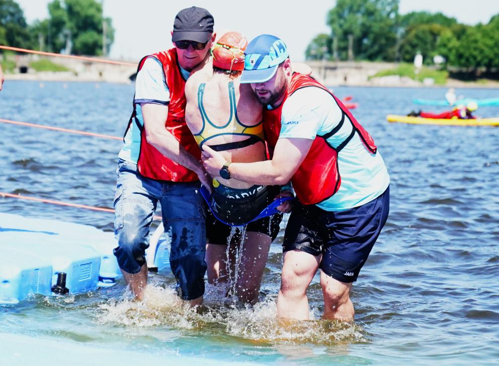 Helfer unterstützen eine Para-Athletin beim Ausstieg aus der Alster.