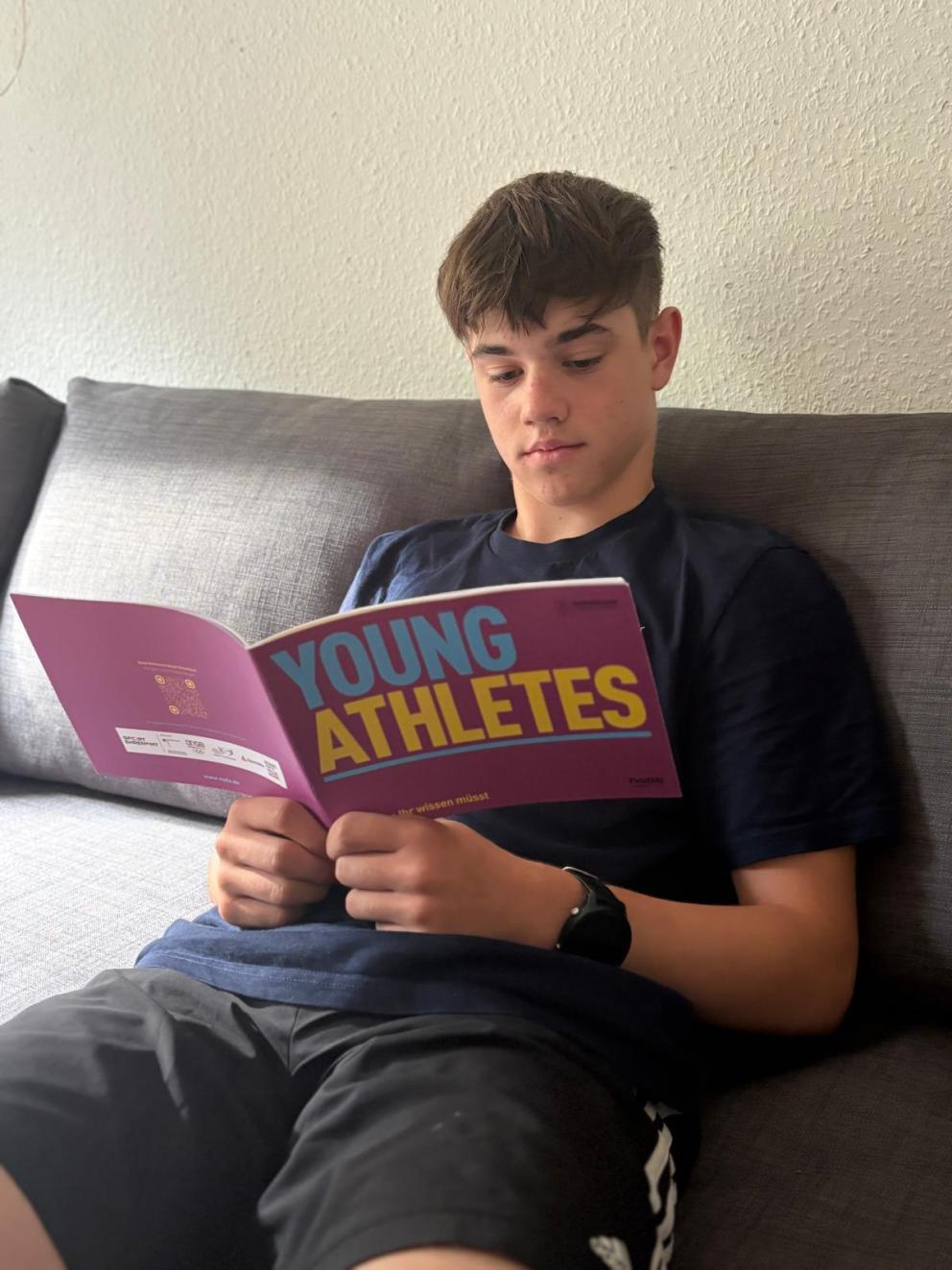 Ein junger Athlet liest die NADA-Broschüre „Young Athletes" zum sauberen Sport.
