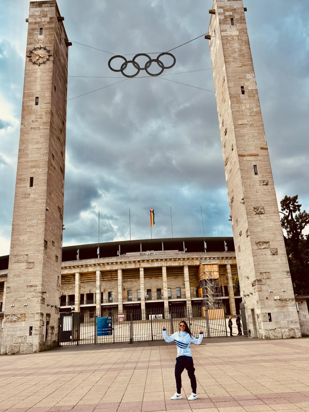TriAktivistin Loreto Cea vor dem Berliner Olympiastadion mit den olympischen Ringen.