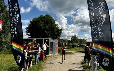 Beim Young-Rebels-Trainingslager des FC St. Pauli läuft eine Teilnehmerin zwischen jubelnden Jugendlichen und den St.-Pauli-Triathlon-Flaggen ins Ziel.